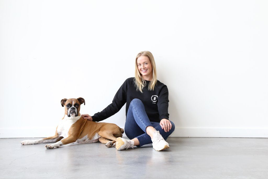 Brunette the Label employee Emma Benneyworth is photographed sitting with a dog at Brunette the Label.