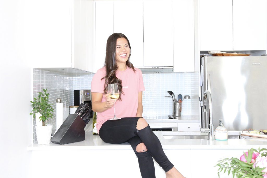 Registered Dietitian Lindsay Pleskot is drinking a glass of white wine in her kitchen.