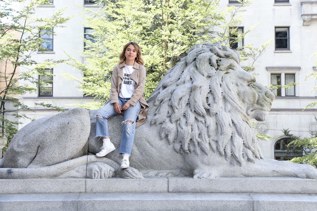 Makeup artist Mereditch Lacosse is photographed sitting on a statue in Vancouver.
