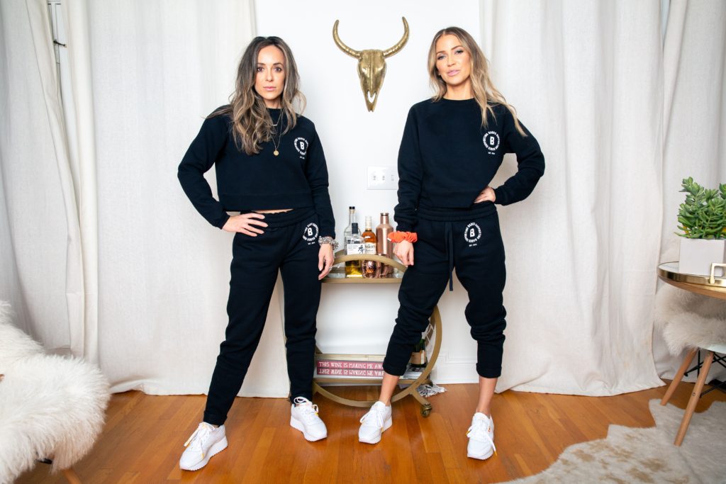 Female entrepreneurs Kaitlyn Bristowe and Clio de la Llave of the Off the Vine podcast are photographed standing in matching Babes Supporting Babes Crew Neck Sweatshirts by Brunette the Label.