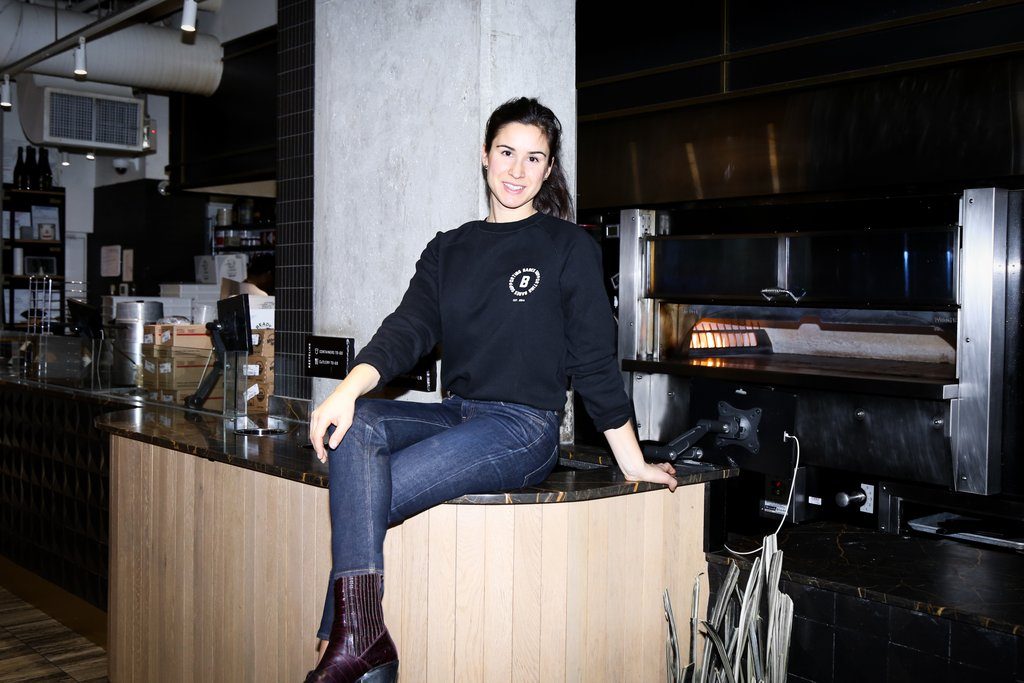 Lia Loukas of Virtuous Pie is photographed sitting on the counter of the plant-based Vancouver restaurant.