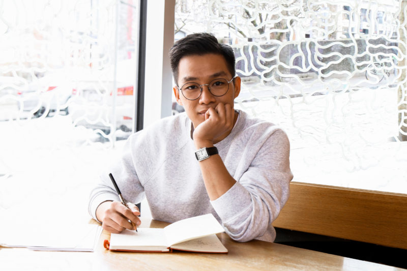 Illustrator of Juno Valentine and The Magical Shoes Derek Desierto is photographed drawing at a Vancouver, BC coffee shop.