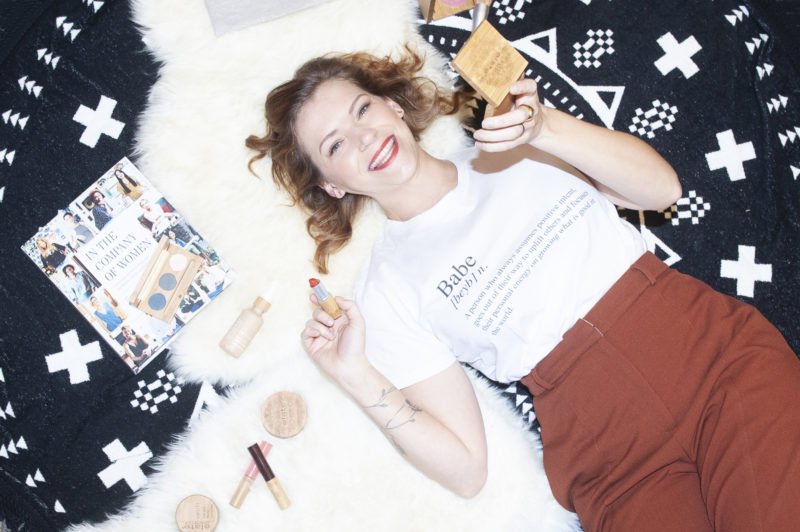 Female entrepreneur Melodie Reynolds is photographed smiling and surrounded by Elate Cosmetics.
