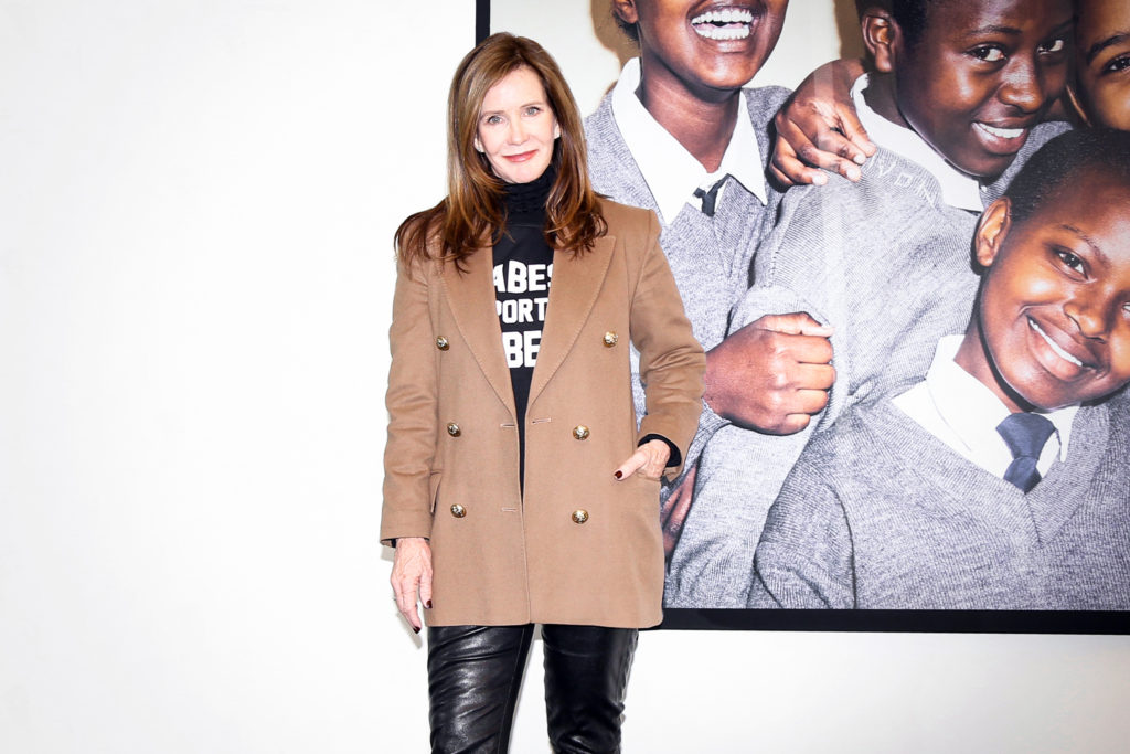 Female entrepreneur Lottie Davis is photographed standing in front of a photograph from the One Girl Can Society.