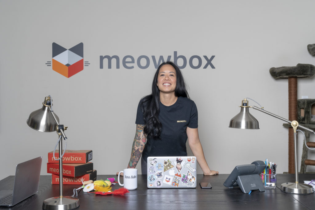 Olivia Canlas, the female entrepreneur behind meowbox, is photographed standing in front of the meowbox logo at the Vancouver head office.