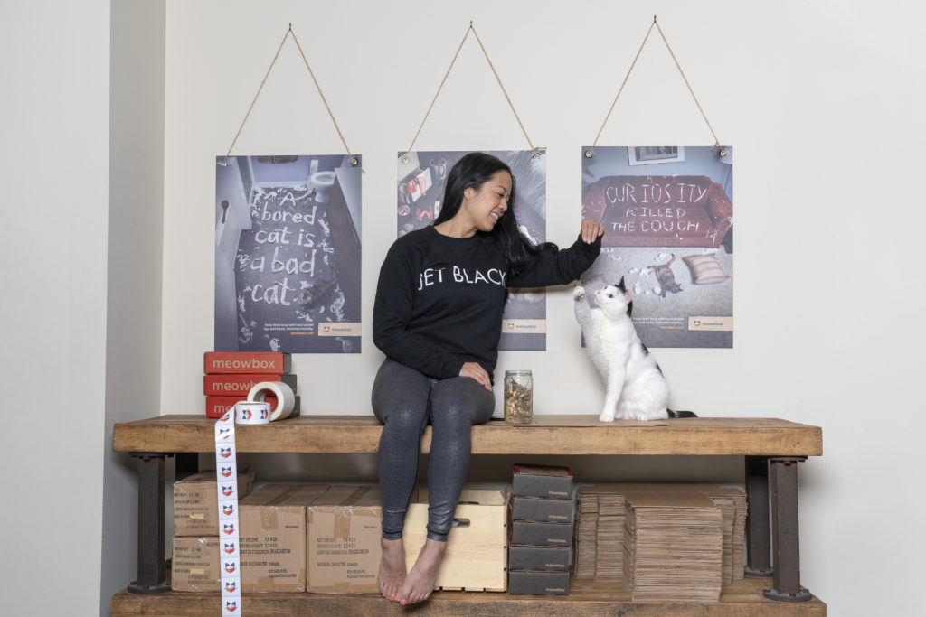 Entrepreneur and meowbox founder Olivia Canlas is photographed playing with her cat.