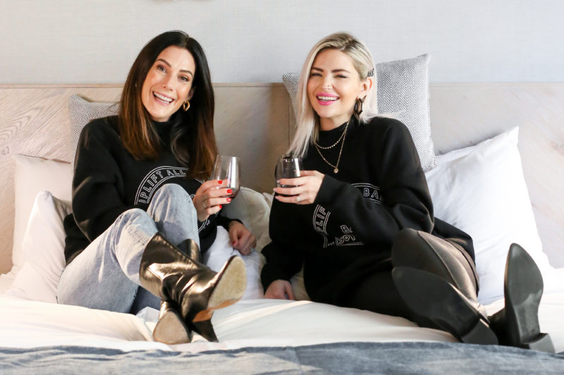 Miriam Alden of Brunette the Label and Sarah Nicole Landry of The Birds Papaya are photographed wearing matching Uplift All Babes Big Sister Crew Neck Sweatshirts by Brunette the Label.